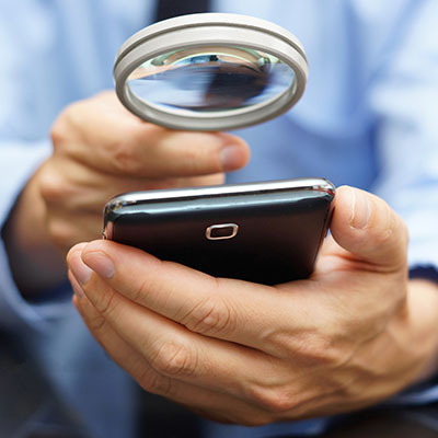 man holding a magnifying glass to look at phone