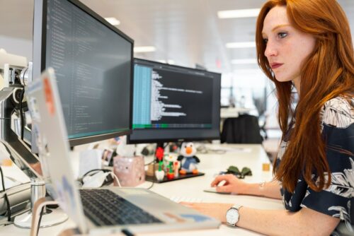 woman in office working on three computers