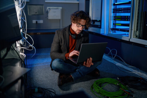 A man sitting in a server room working
